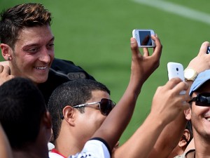 Germany's midfielder Mesut Ozil (L) poses with fans taking pictures after a training session of Germany's national football team in Santo Andre on June 9, 2014 ahead of the 2014 FIFA World Cup football tournament. AFP PHOTO / PATRIK STOLLARZ        (Photo credit should read PATRIK STOLLARZ/AFP/Getty Images)